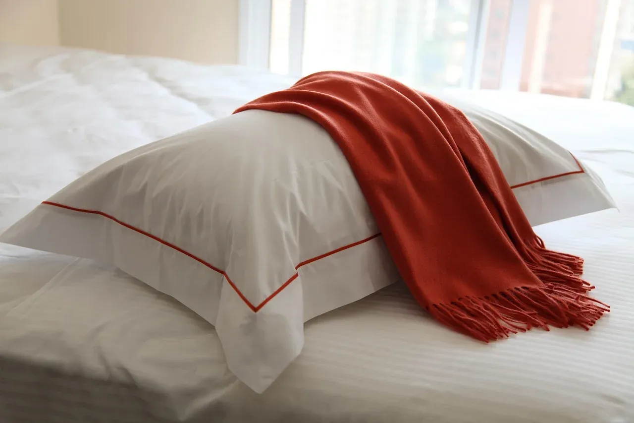 White duvet and pillows with a red throw