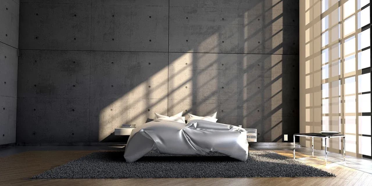 Sunlight crossing a bed and concrete bedroom wall