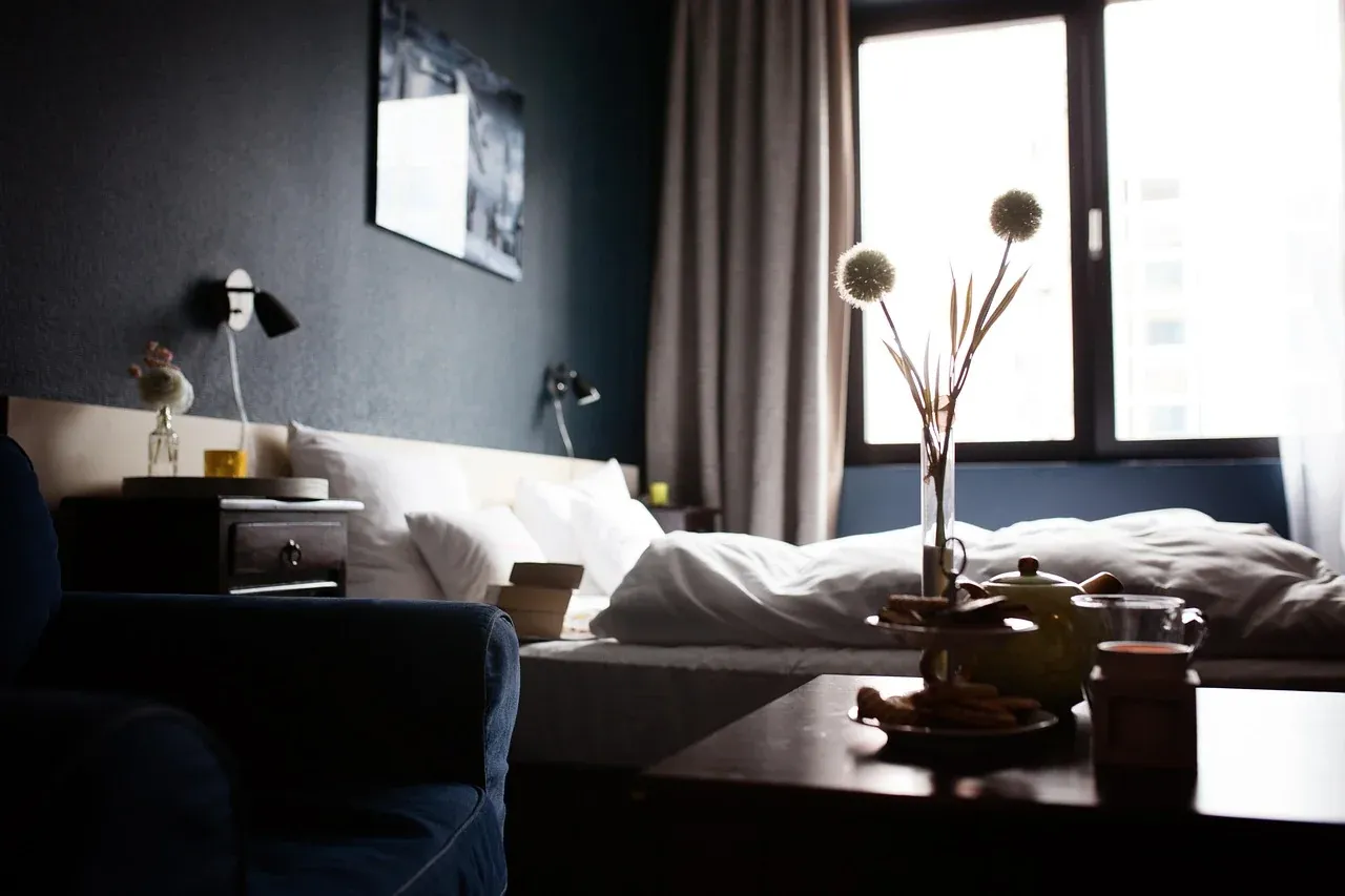 Dark bedroom with layered pillows and a bedside lamp