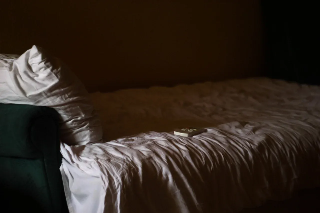 Dark bedroom with a textured duvet and white pillow