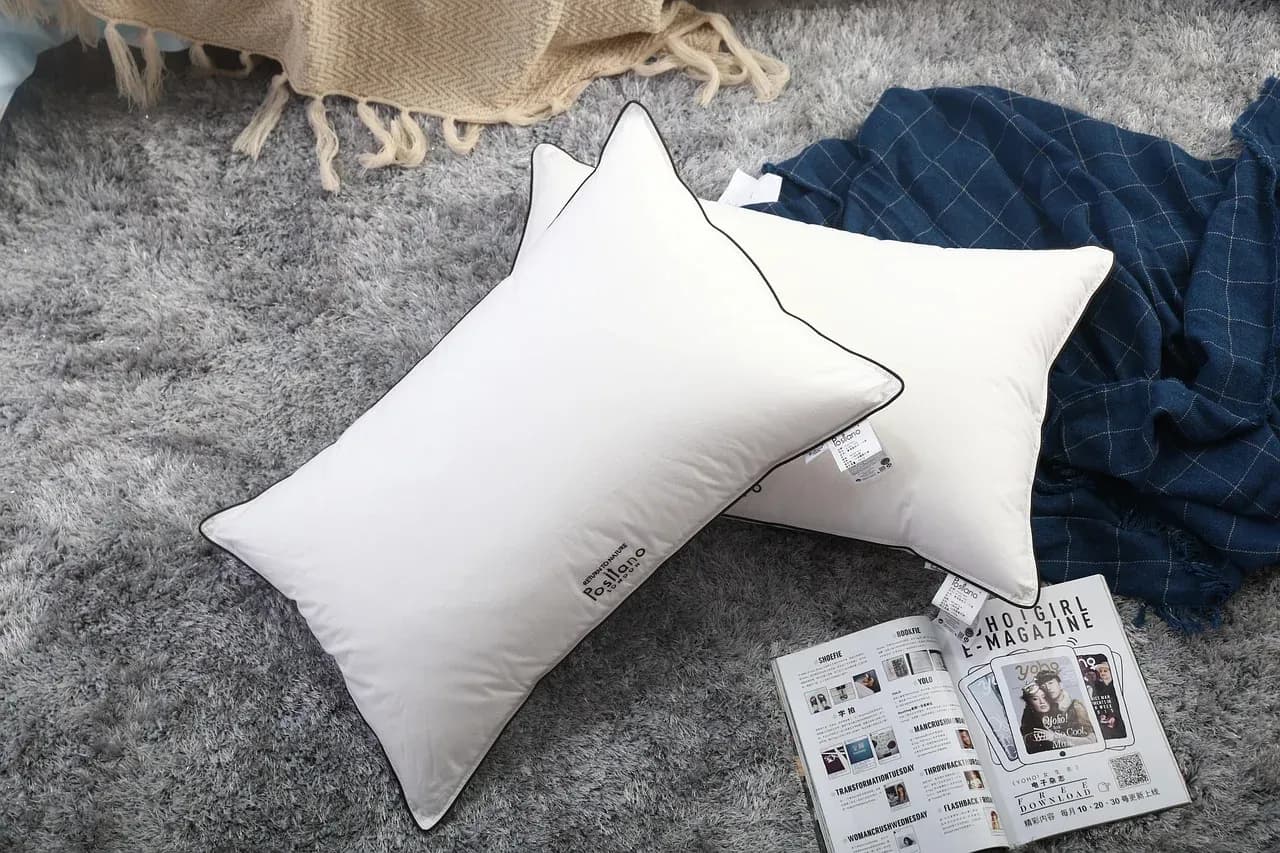 Two white pillows beside a folded dark textile