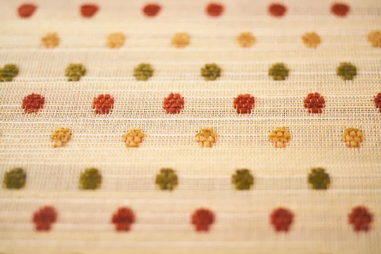 Close-up of cream fabric with a small coloured pattern