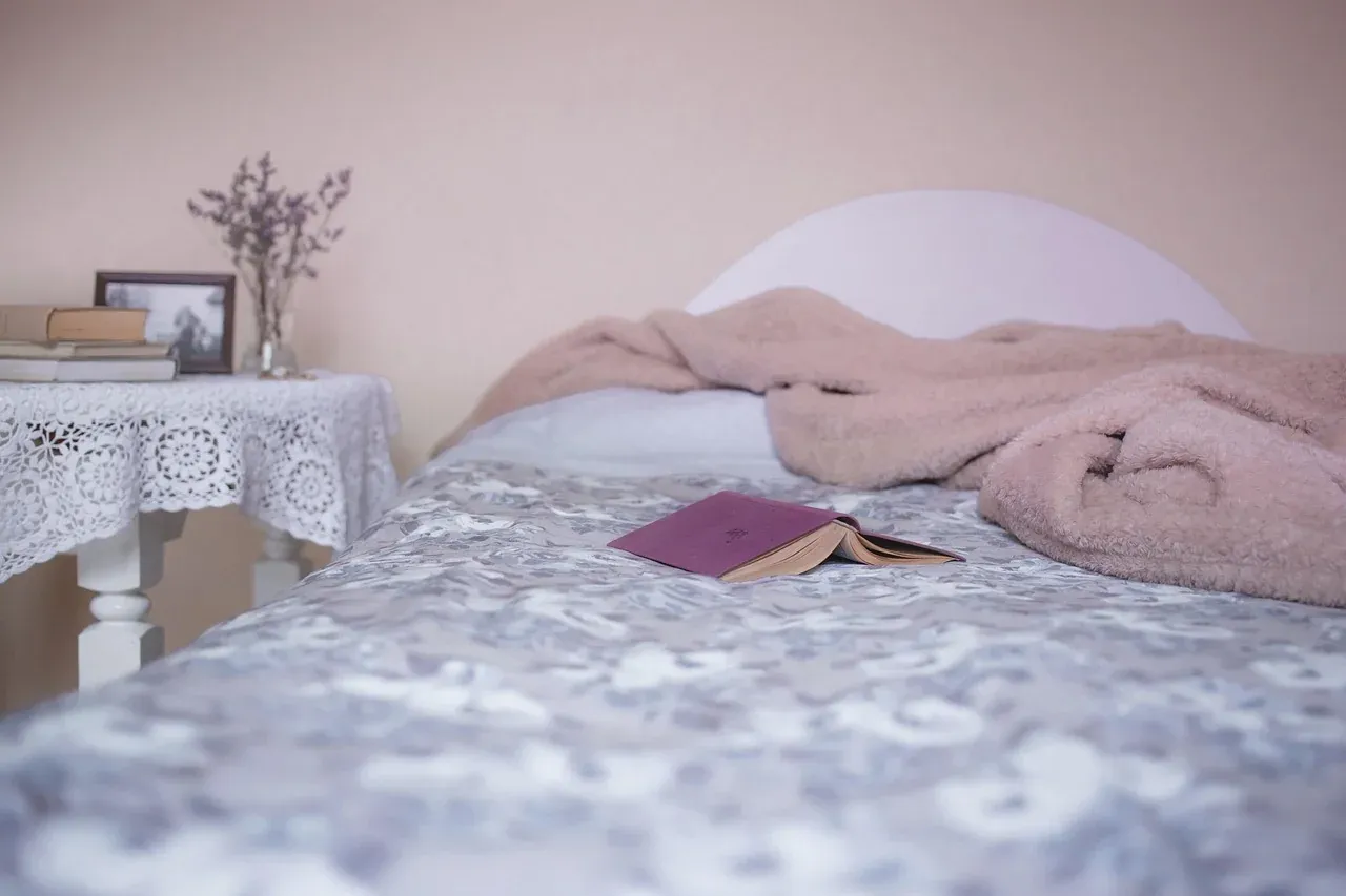 Bed with a pink cover and a floral sheet