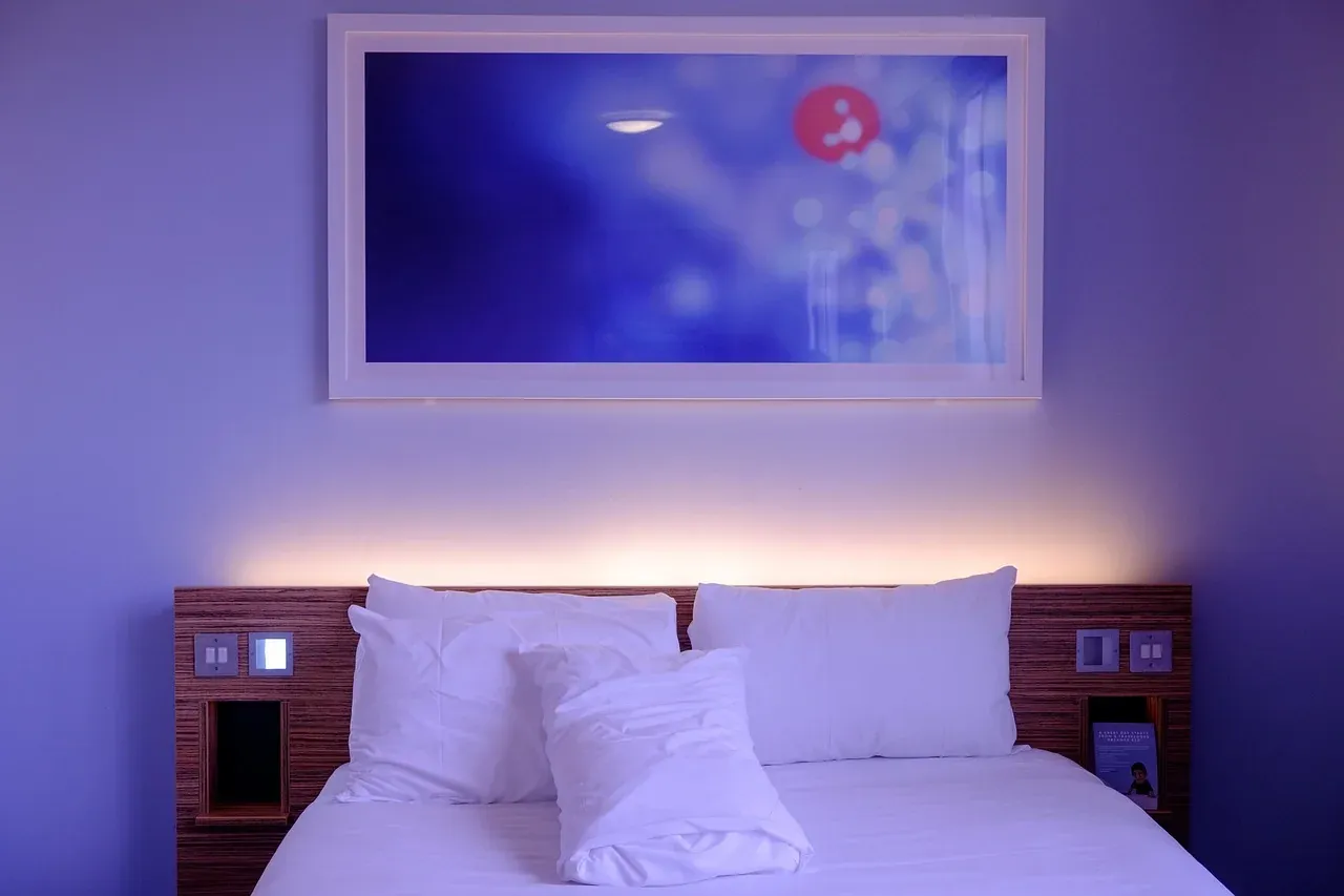 Hotel bed with white pillows and blue ambient lighting