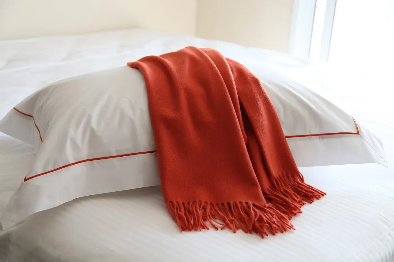White bedding with a red throw draped across it