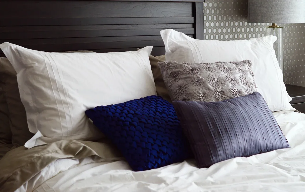 White and blue pillows against a dark wooden headboard