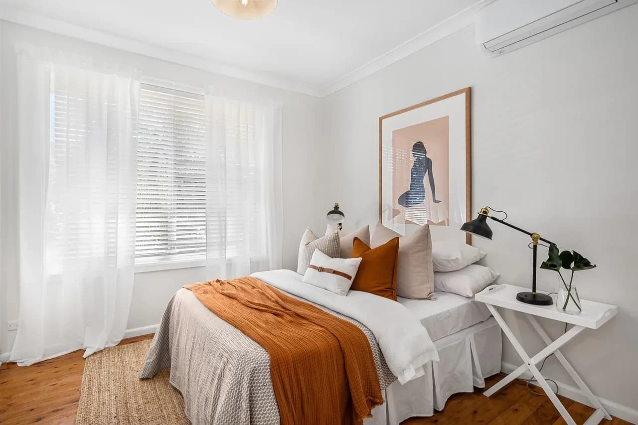 White bed with an orange throw in a bright room
