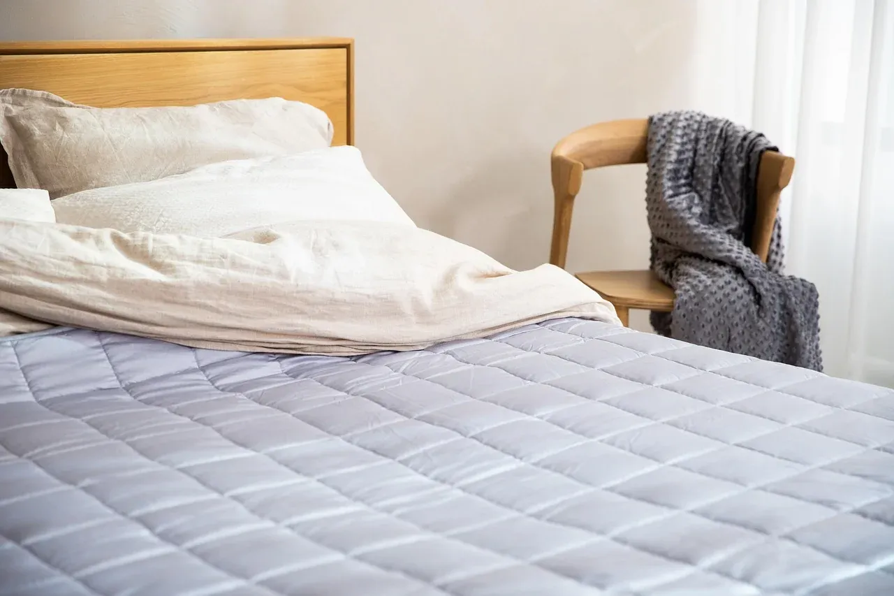 Bed with a pale quilted cover and a wooden frame