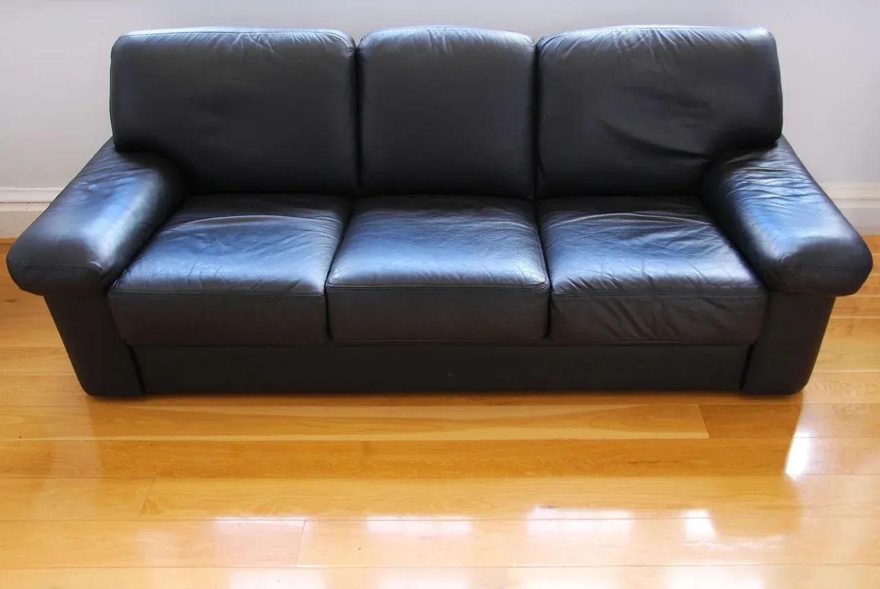 Black leather sofa on a wooden floor