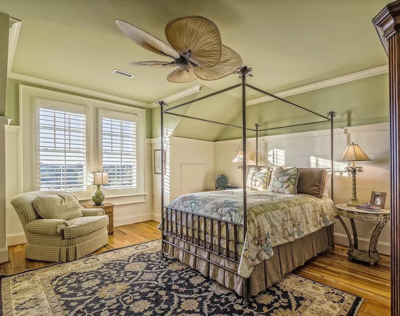Four-poster bed in a bright room with window shutters