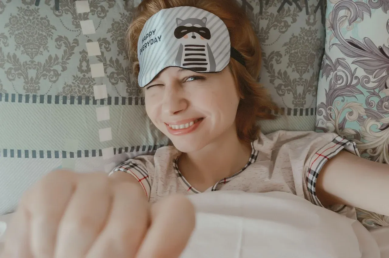 Woman resting in bed with a sleep mask on her forehead