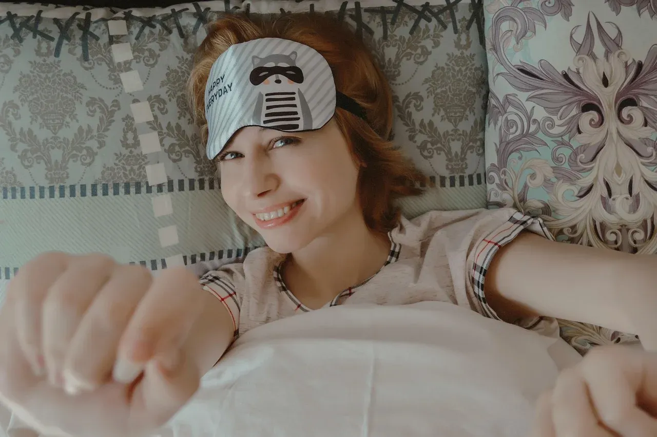 Woman sitting in bed with a sleep mask on her forehead