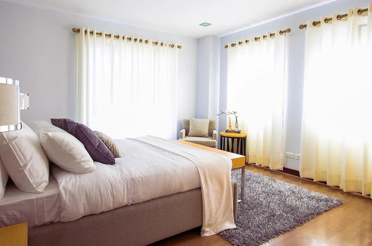 Made bed with white linen and a cream throw