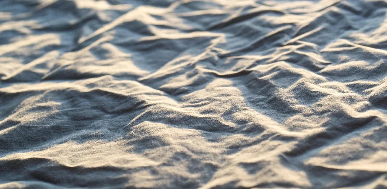 Close-up of soft folds in pale bedding fabric