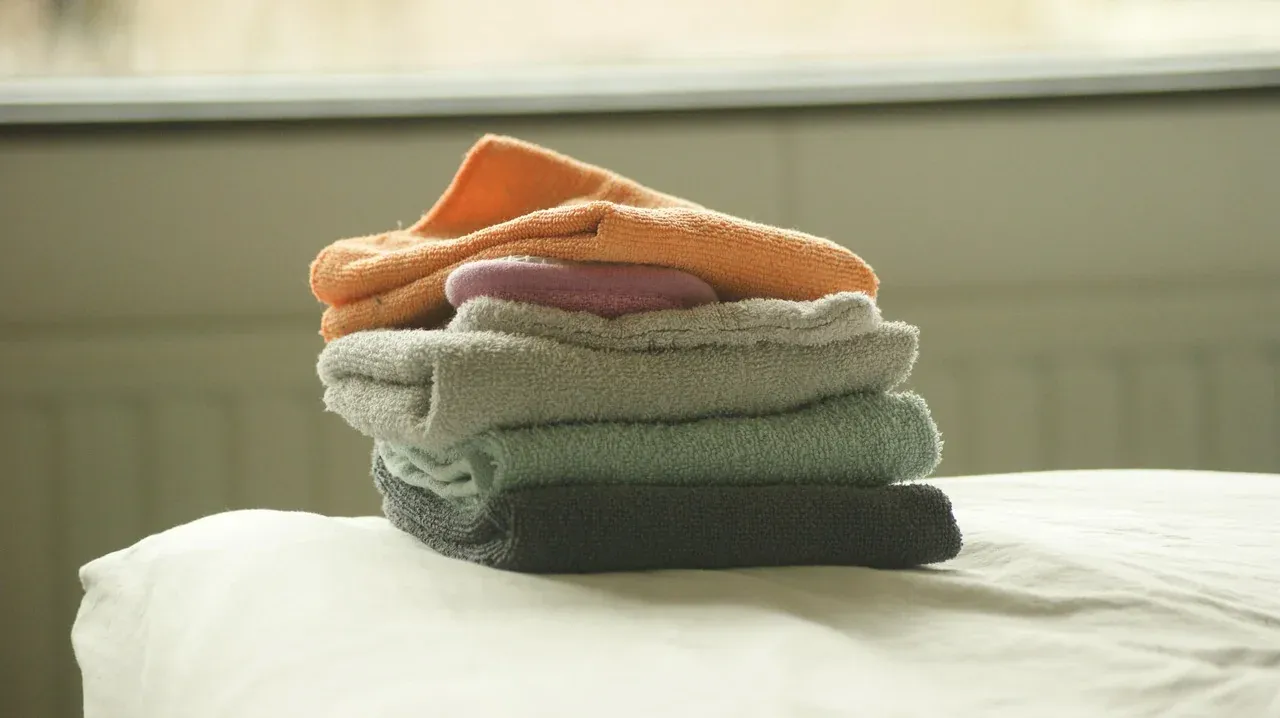 Freshly folded towels stacked on a bed
