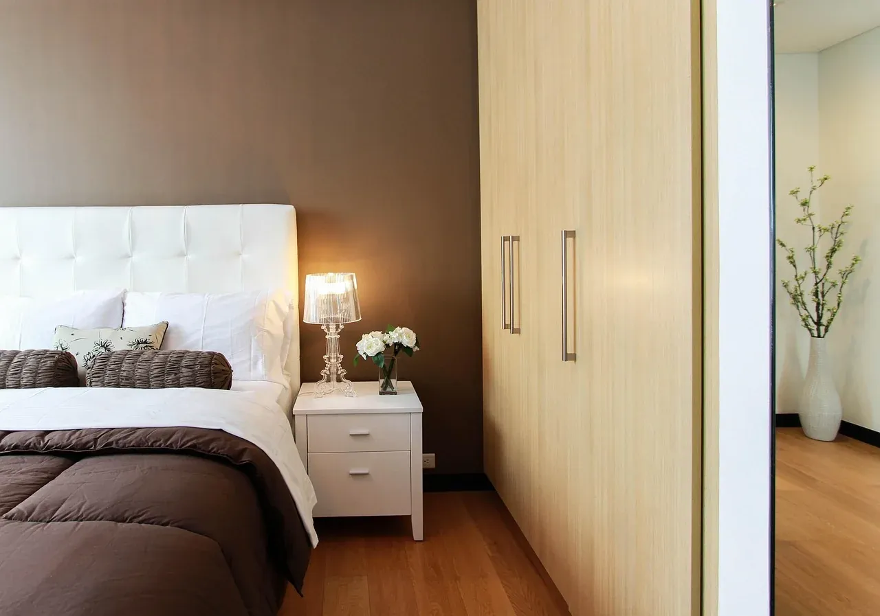 Made bed beside a white bedside cabinet