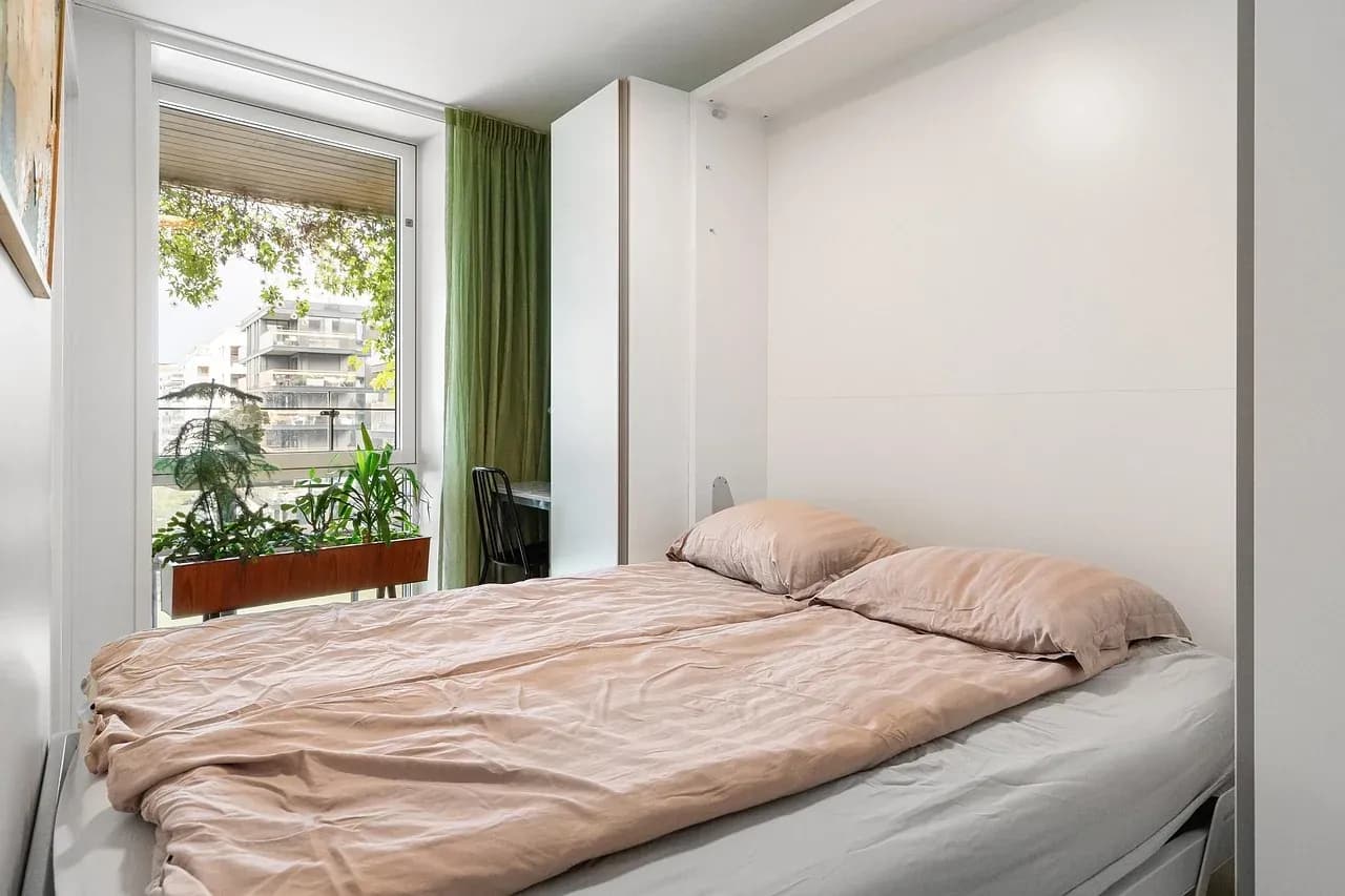 Soft bedding beside a bright bedroom window
