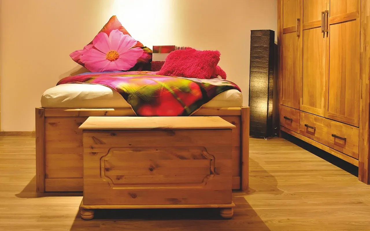 Single bed with colourful bedding and a wooden storage chest