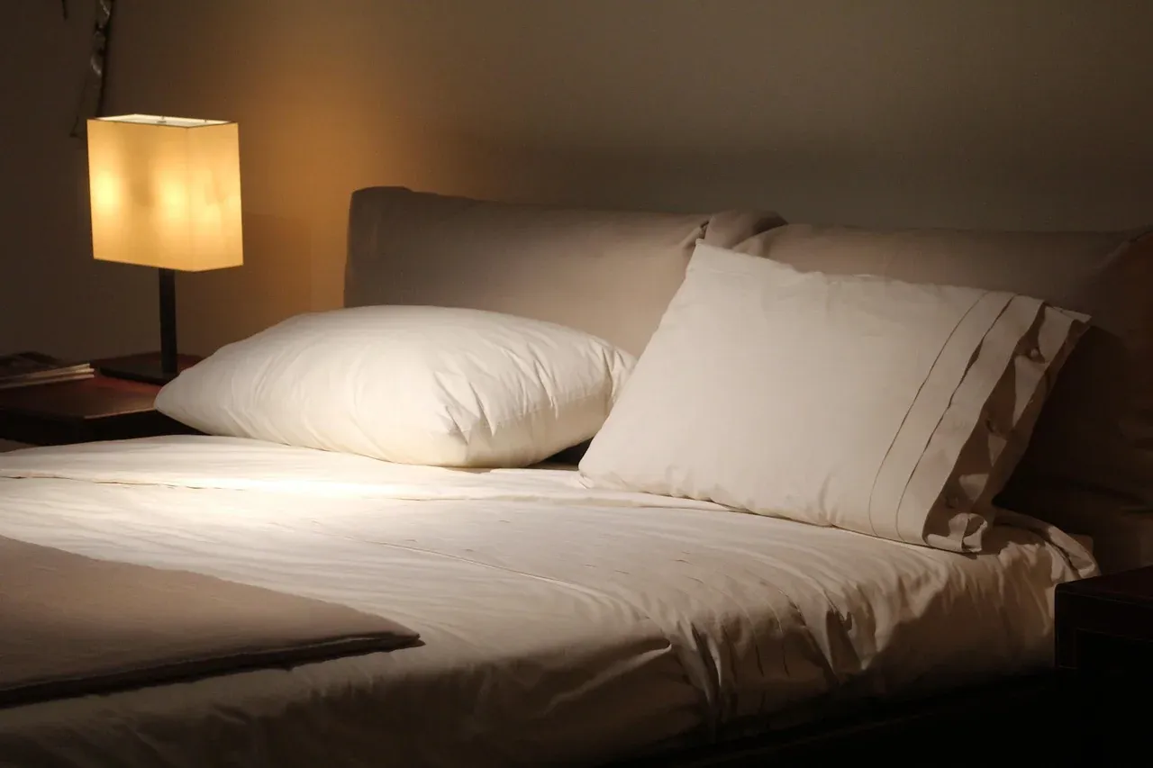 White pillows and sheets beside a bedside lamp